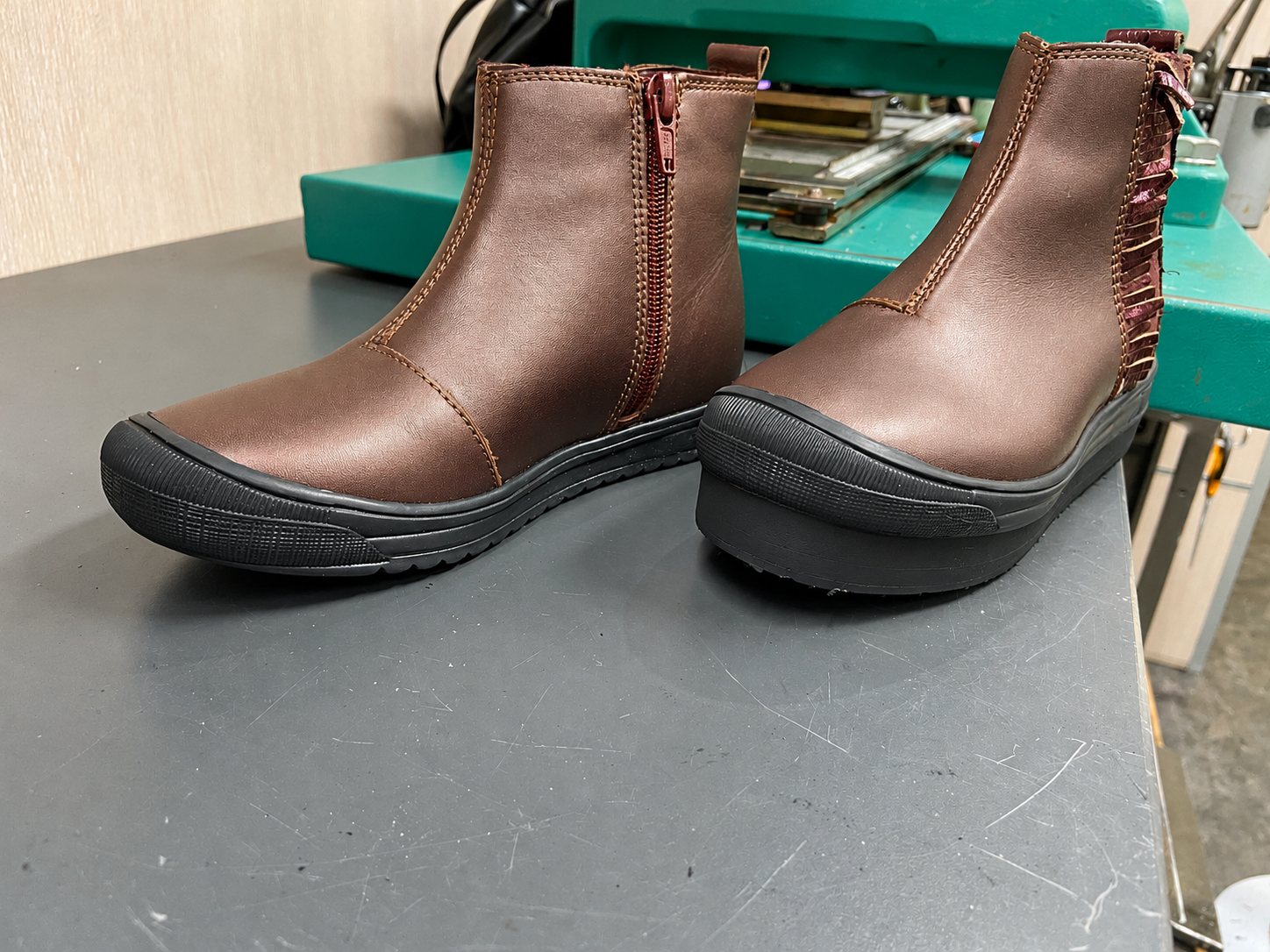 Paire de bottines en cuir bordeaux métallisé sur établi d'atelier